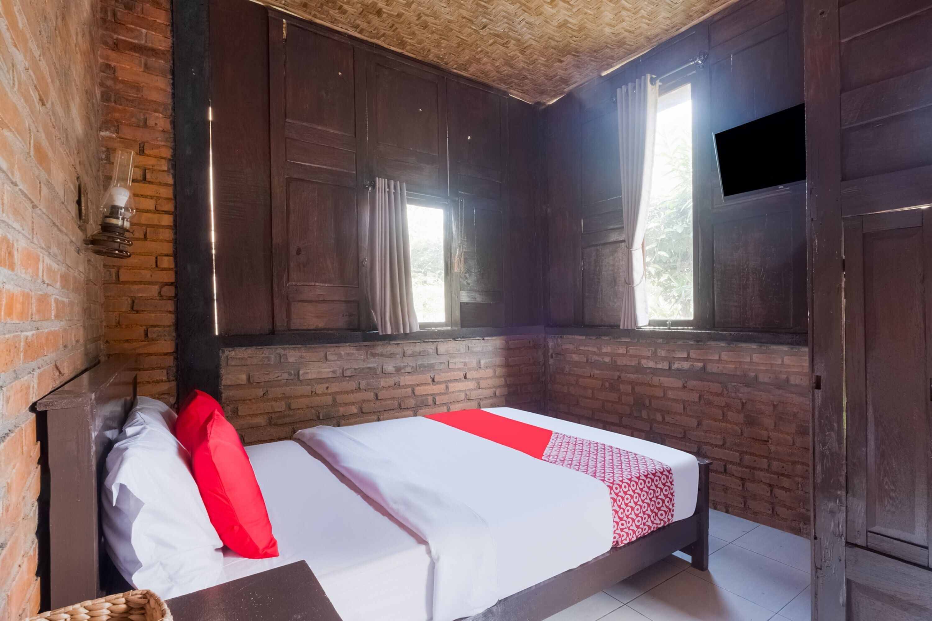 A room with a bed, wooden walls, a brick wall, and a window.