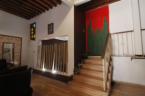 Staircase leads to an upper level with a door at the top, surrounded by potted plants and a mirror.