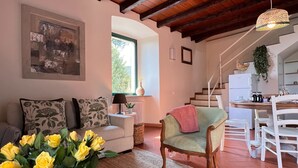 A spacious living area with a high wooden ceiling, a dining table with chairs, a sofa, and a vase of yellow flowers. - Apartment "La Brezza" (Cavallasca)
