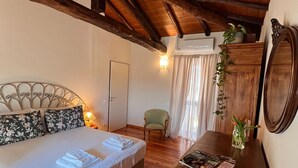 A bedroom with a wooden ceiling, a bed with floral pillows, a wooden dresser, and a chair. - Apartment "La Brezza" (Cavallasca)