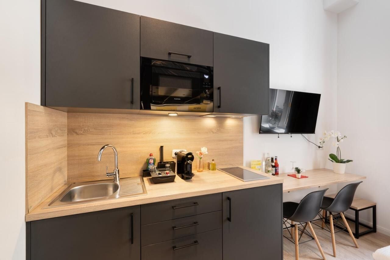 Une cuisine moderne équipée d’un four à micro-ondes encastré, d’un évier et d’un coin repas avec deux chaises.
