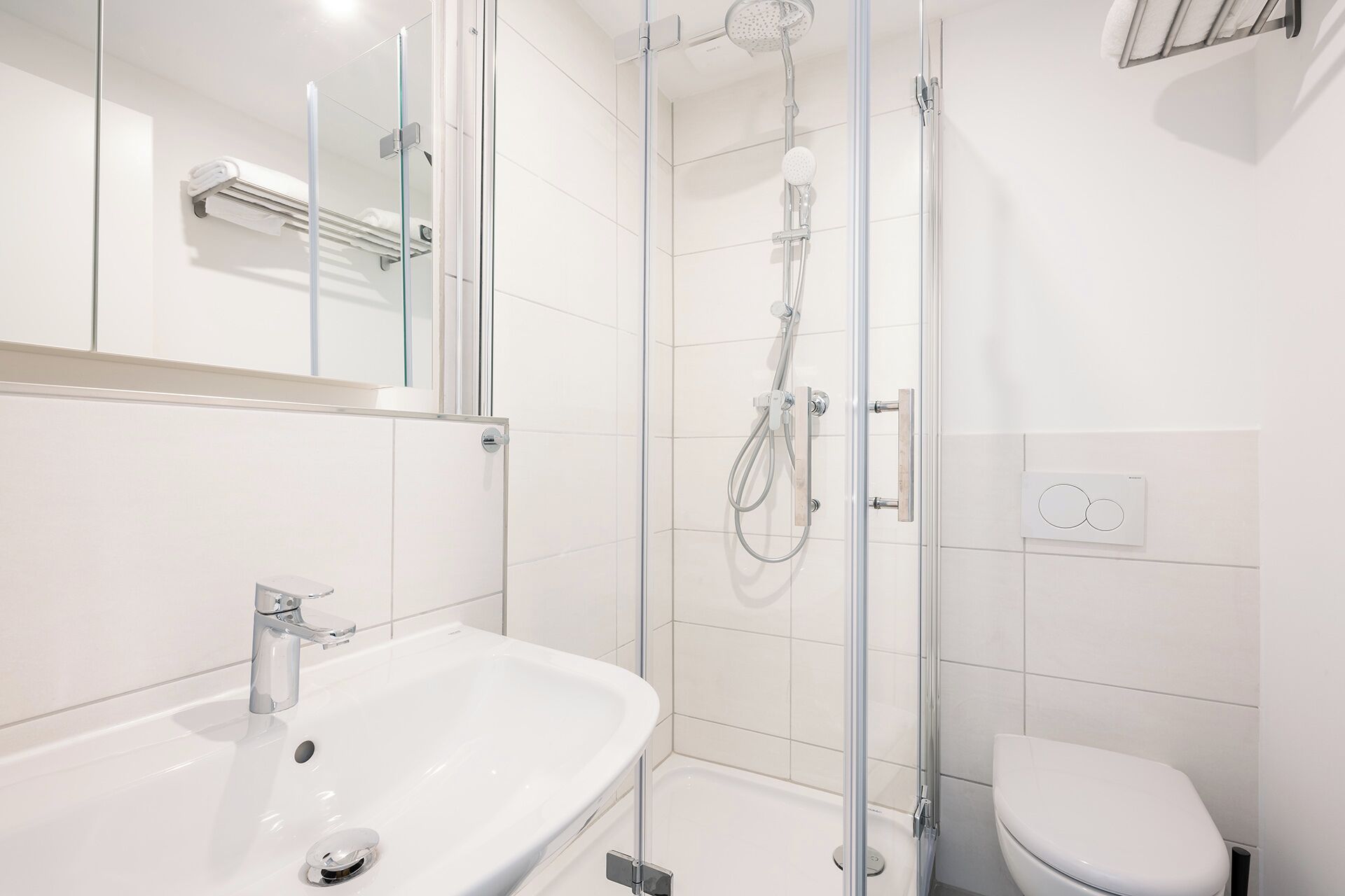 A modern bathroom with a glass-enclosed shower, a white sink, and a toilet.