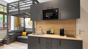 A compact kitchen with a built-in microwave, a sink, and a wooden countertop. - Servus Apartments by Homaris (Munich)