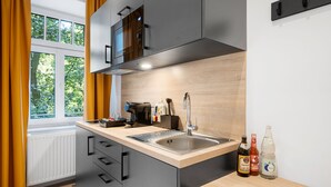 A modern kitchen with a built-in stove, a sink, and a window with curtains. - Servus Apartments by Homaris (Munich)