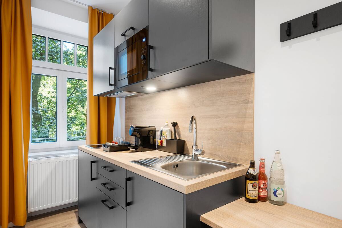 Une cuisine moderne équipée d’une cuisinière intégrée, d’un évier et d’une fenêtre avec des rideaux.