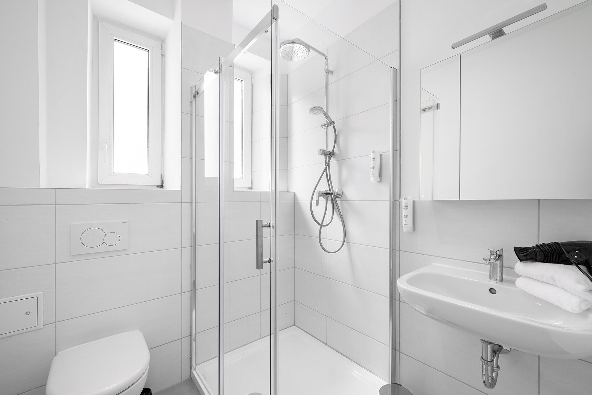A modern bathroom with a glass-enclosed shower, a white sink, and a toilet.
