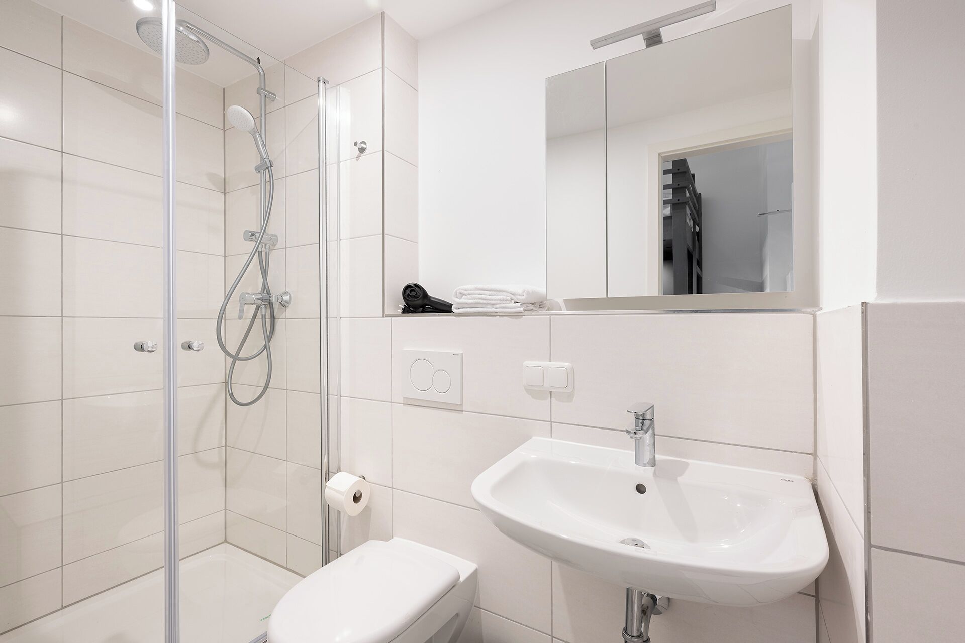 A modern bathroom with a glass-enclosed shower, a white sink, and a toilet.