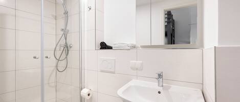 A modern bathroom with a glass-enclosed shower, a white sink, and a toilet.