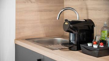 Una cuina moderna amb un rentaplat amb encastrament, una cafetera i un suport per a càpsules de cafè.