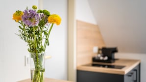A clear glass vase with flowers on a wooden table in a modern kitchen setting. - Servus Apartments by Homaris (Munich)