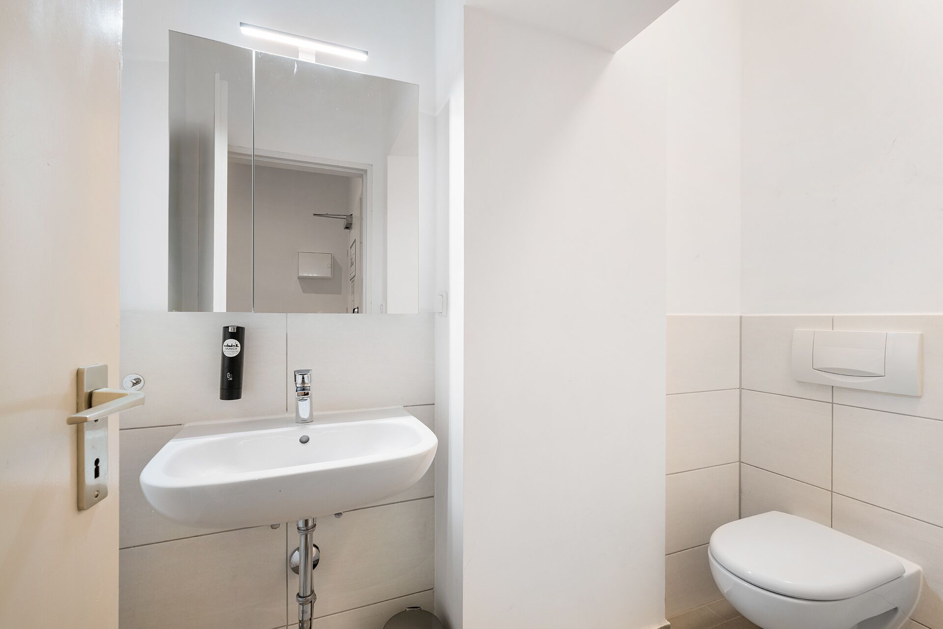 A bathroom with a white sink, a mirror, and a toilet.