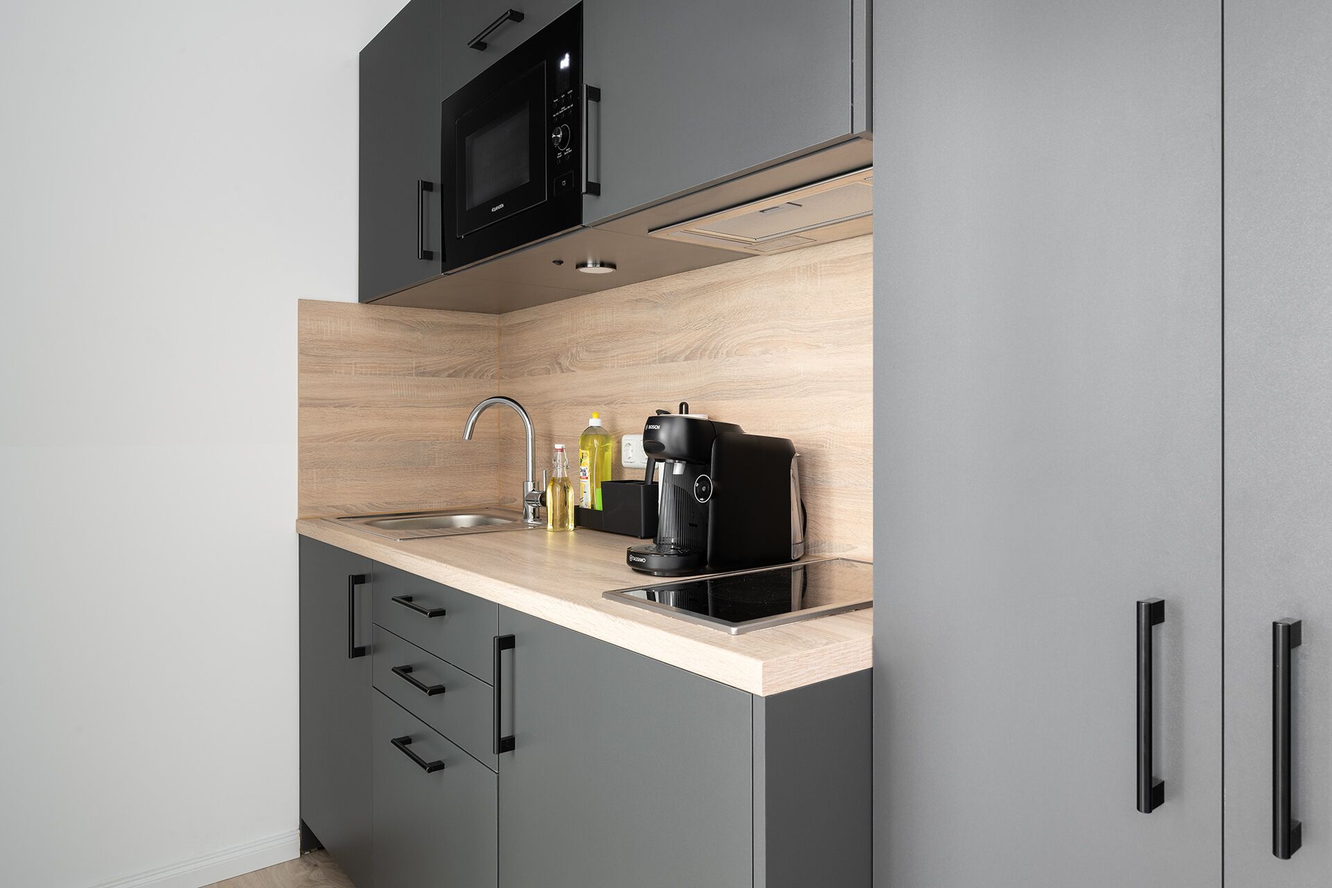 Eine moderne Küche mit Einbau-Mikrowelle, Kaffeemaschine und Spüle.