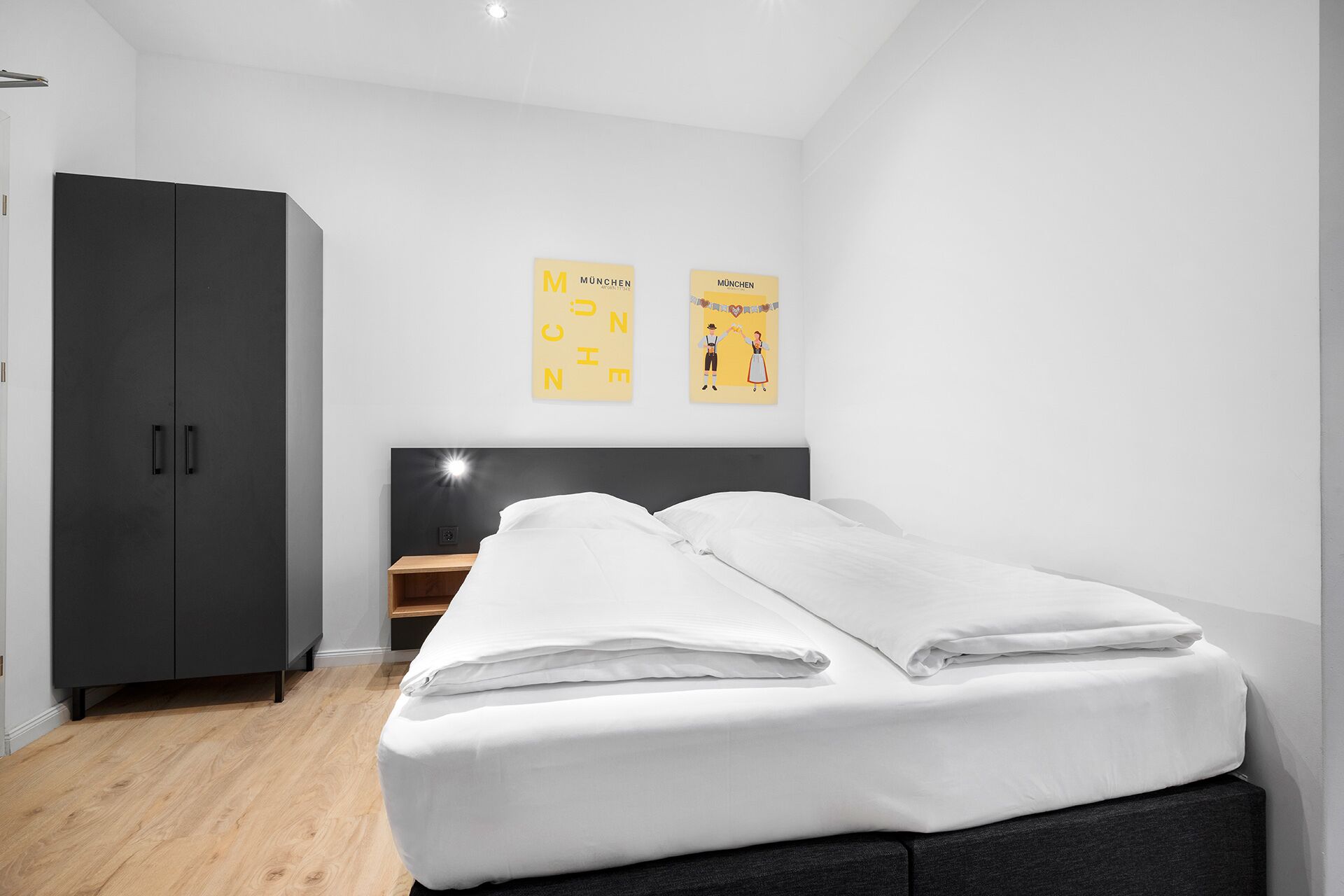 Un dormitorio moderno con una cama, un armario y dos carteles en la pared.