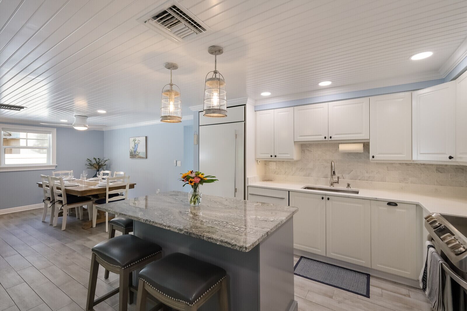 Una cocina moderna con armarios blancos, encimera de granito y campana extractora de acero inoxidable.
