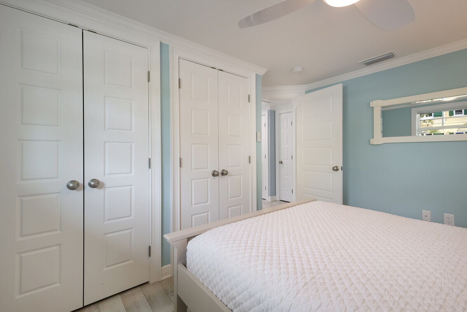 A bedroom with a bed, white wardrobe, and a ceiling fan.