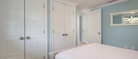 A bedroom with a bed, white wardrobe, and a ceiling fan.