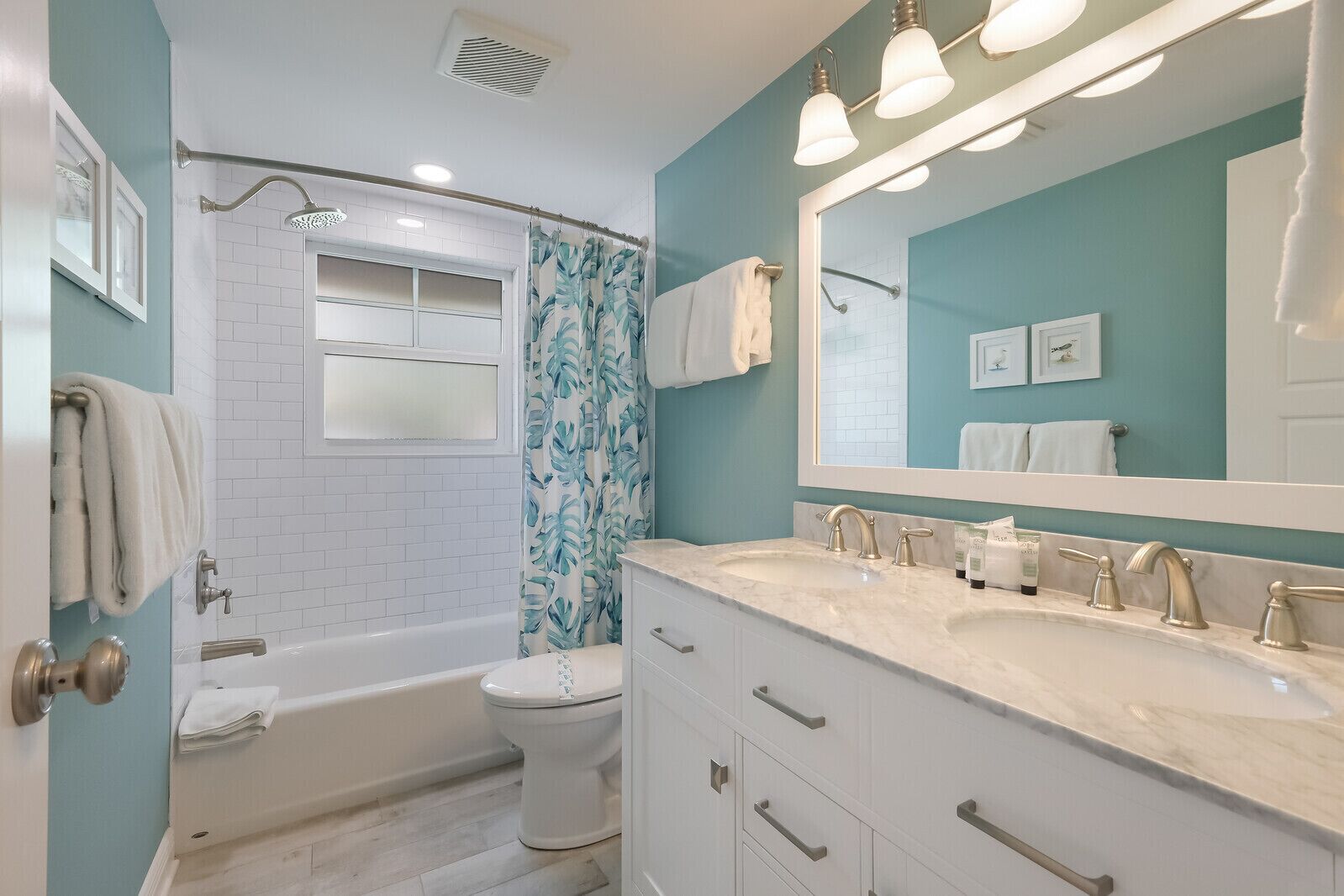 Un baño moderno con bañera, inodoro y tocador con un espejo grande.