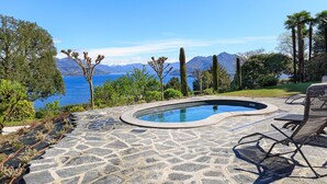 Une piscine en pierre offrant une vue sur la mer et les montagnes.