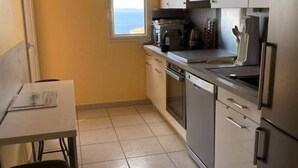 Une cuisine de taille réduite, avec une fenêtre, une table et une chaise.