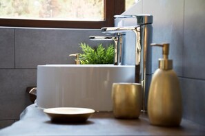 Un baño moderno con un grifo de cromo elegante, un lavabo blanco y una pequeña planta en maceta.