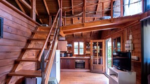 A wooden cabin interior with a kitchen, dining area, and a staircase leading to an upper level. - La Peña Luxury Tarifa (Tarifa)