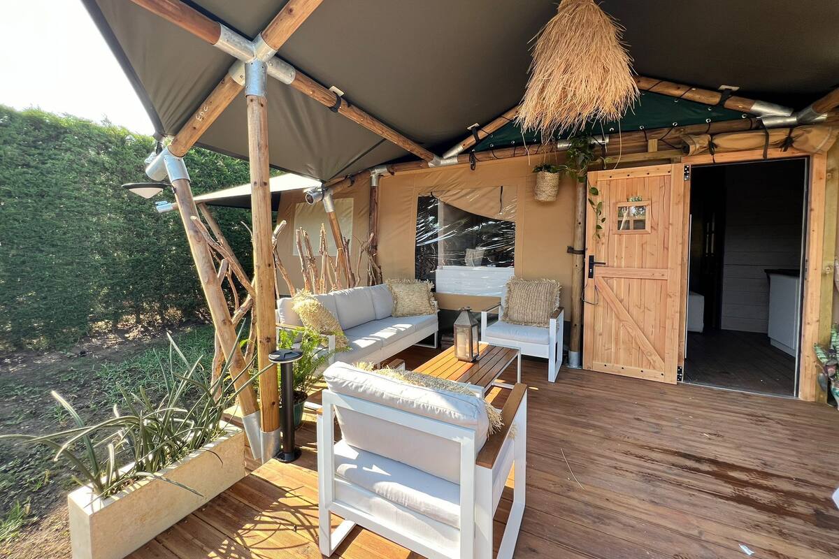 A wooden deck with a covered seating area, a hanging lantern, and a door leading to an interior space.