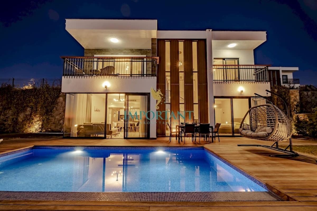 Uma casa moderna de dois andares com piscina, móveis de exterior e uma varanda.