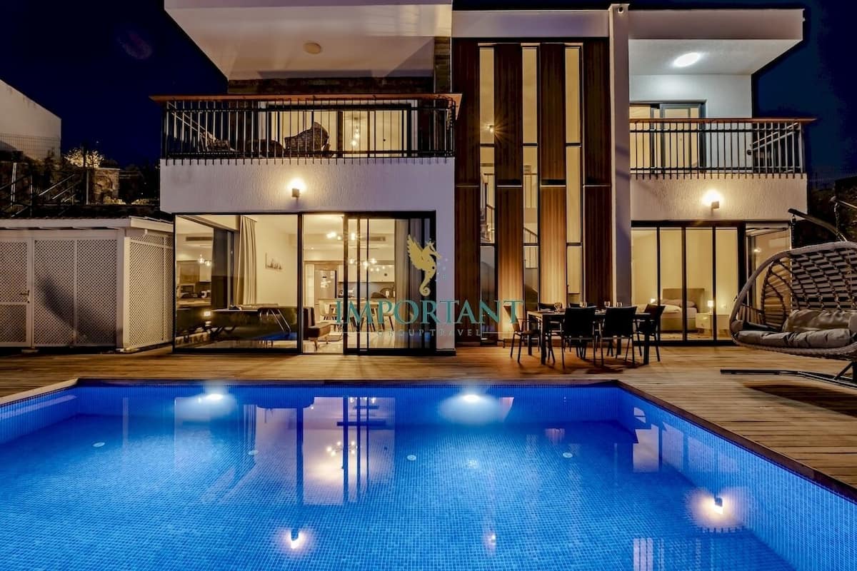 Um edifício moderno de dois andares com piscina, área de estar ao ar livre e um restaurante visível.