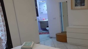 A bedroom with a bed, a bedside table, a wardrobe, and a bathroom visible through an open door. - Olbia, Near Costa Smeralda Airport - Non-smoking (Olbia)