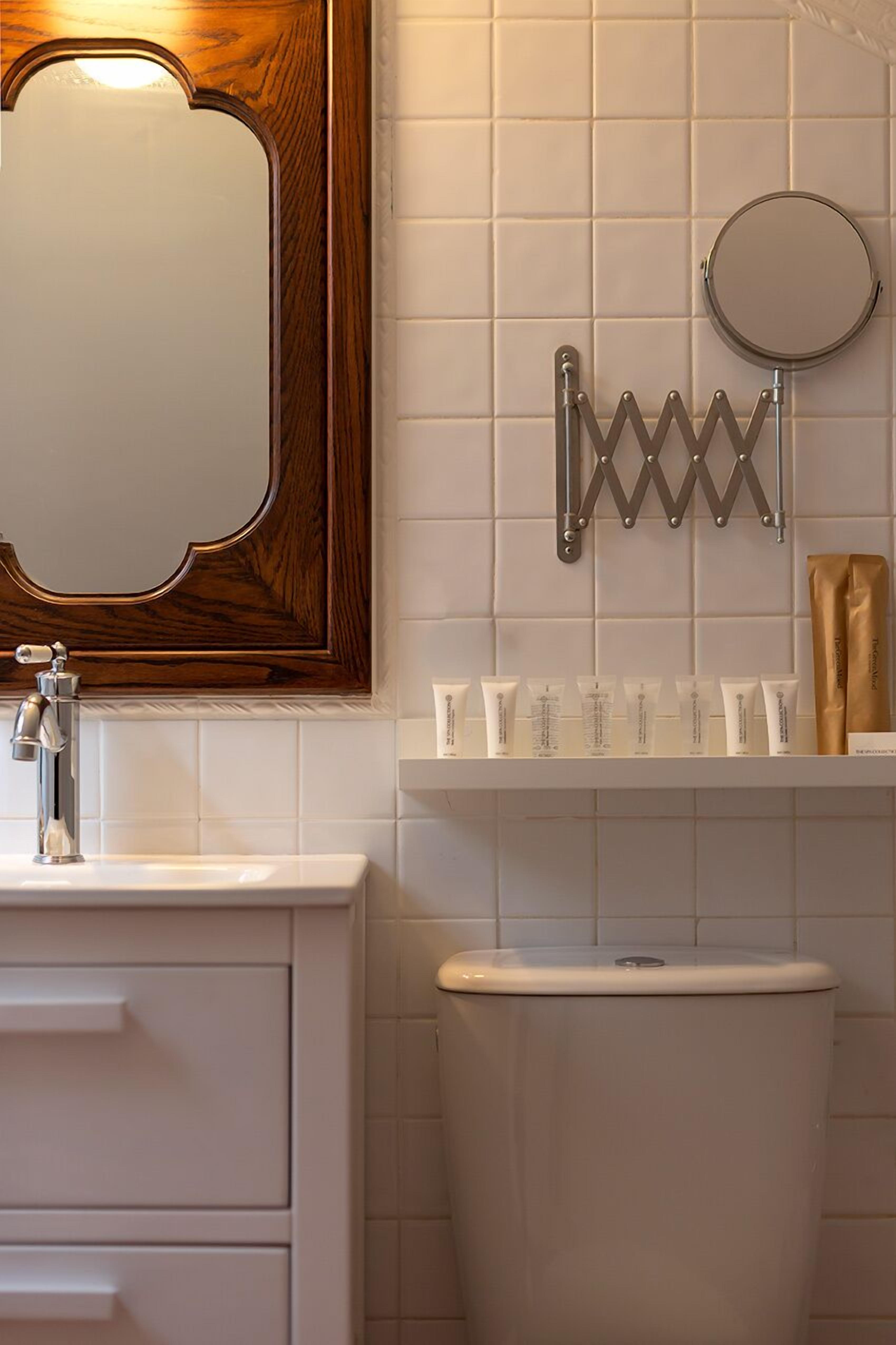 Un baño con un espejo de marco de madera, un lavabo blanco y un inodoro.