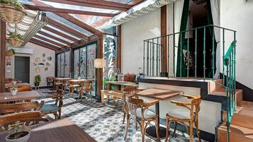 A cozy cafe with wooden tables and chairs, a tiled floor, and a green staircase.