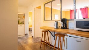Una cocina compacta con encimera de madera, dos taburetes, una cafetera y un microondas.