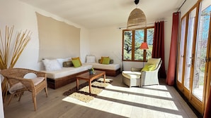 A cozy living room with a sofa, armchairs, a coffee table, and a large window with curtains.
