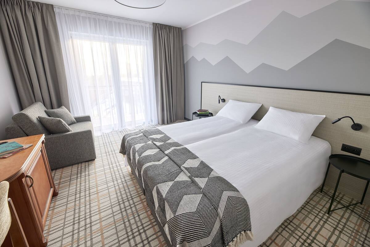 A hotel room with a large bed, a sofa, a desk, and a nightstand.
