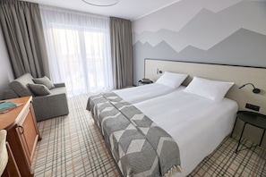 A hotel room with a large bed, a sofa, a desk, and a nightstand. - Resort Karkonosze (Stara Kamienica)