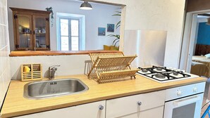 Una cocina con un lavamanos, tendedero de madera, estufa y armarios.