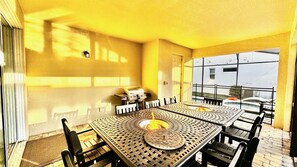 A sunlit patio with a table and chairs, a grill, and a view of a building through a glass door. - Pool, Spa, Game Room, Theater, 4 Miles to Disney! (Kissimmee)