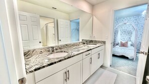 A bathroom with two sinks, a large mirror, and a view of a bedroom with a bed and a canopy. - Pool, Spa, Game Room, Theater, 4 Miles to Disney! (Kissimmee)