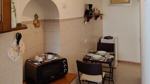 Een kleine keuken met een broodrooster, een koffiezetapparaat en een eethoek met een tafel en stoelen.