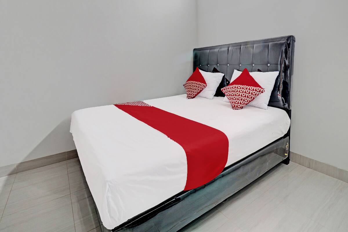 Een moderne hotelkamer met een bed, wit beddengoed en rode accenten.