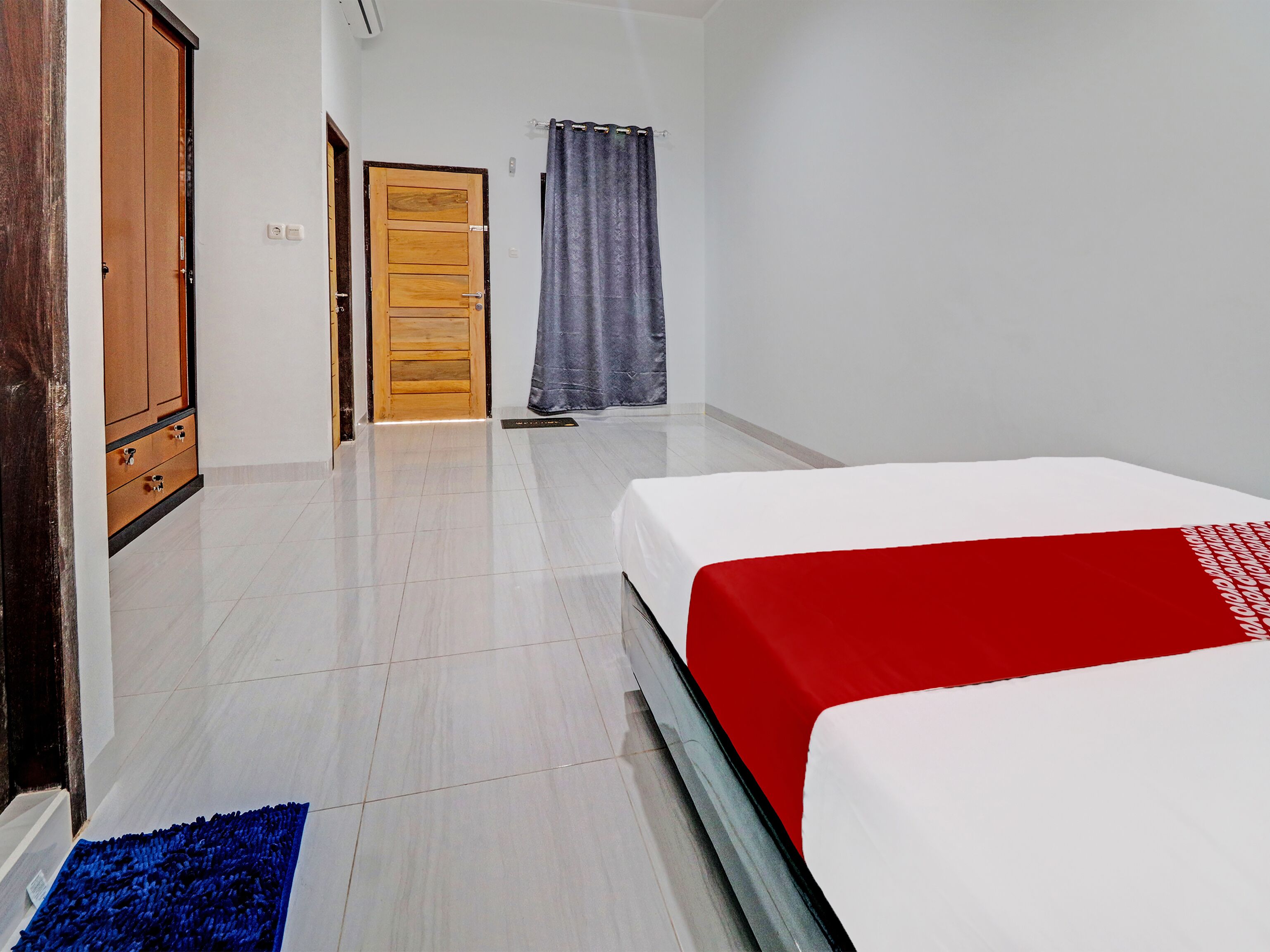 Ein Hotelzimmer mit einem Bett, einem Holzschrank, einer Tür und einem Vorhang.