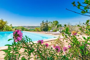 A swimming pool with lounge chairs, surrounded by greenery and a clear sky. - Italian Experience - Casa Bellavista (Ostra)