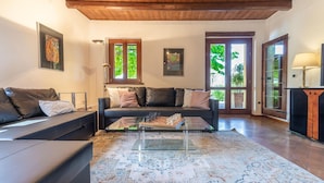 A modern living room with a sofa, a coffee table, and a rug. There are windows with curtains, a lamp, and artwork on the walls. - Italian Experience - Casa Bellavista (Ostra)