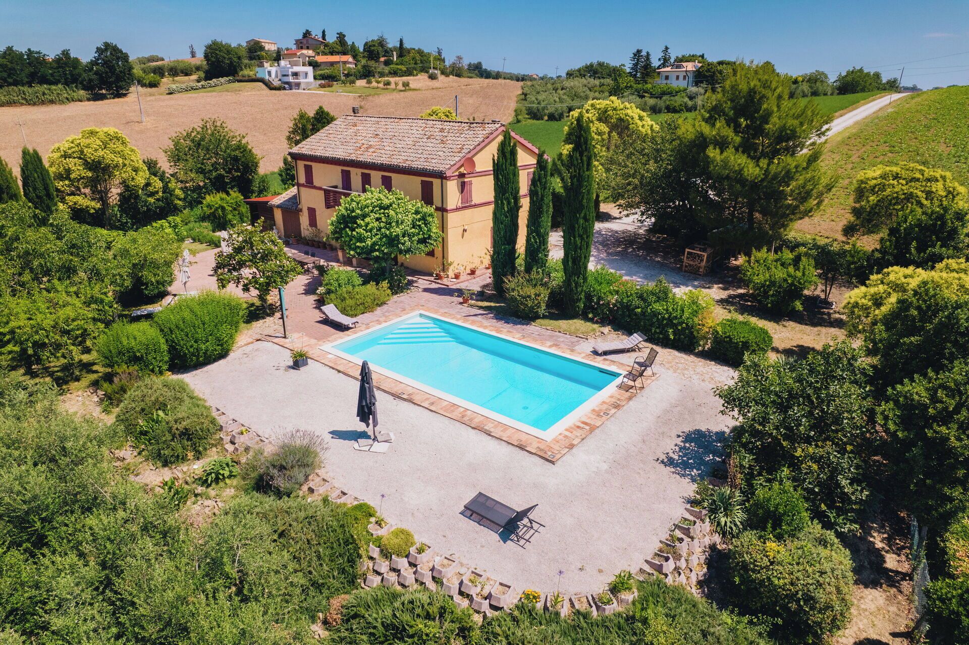 Une vue aérienne d’une propriété dotée d’une piscine, entourée de verdure et d’un petit bâtiment.