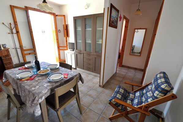 Un comedor con una mesa dispuesta para cuatro, una silla de madera, un armario y un espejo.