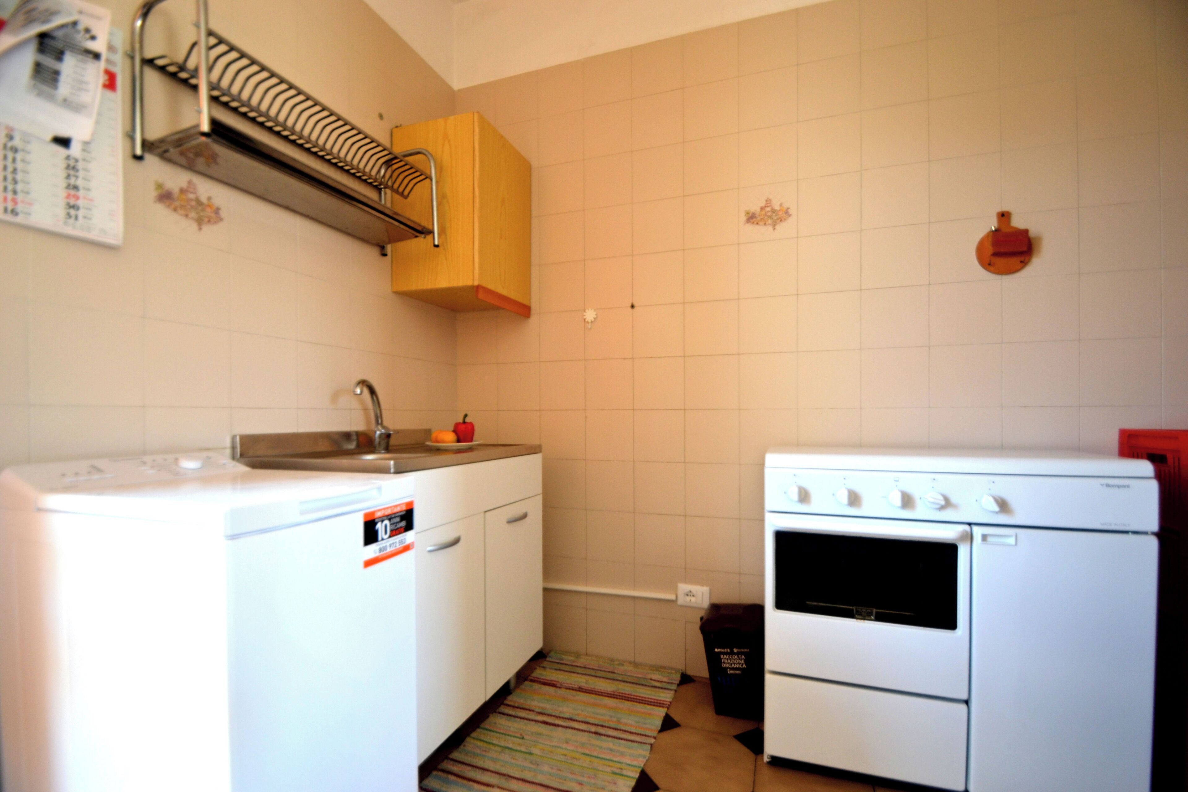 A compact kitchen with a washing machine, a stove, and a sink.