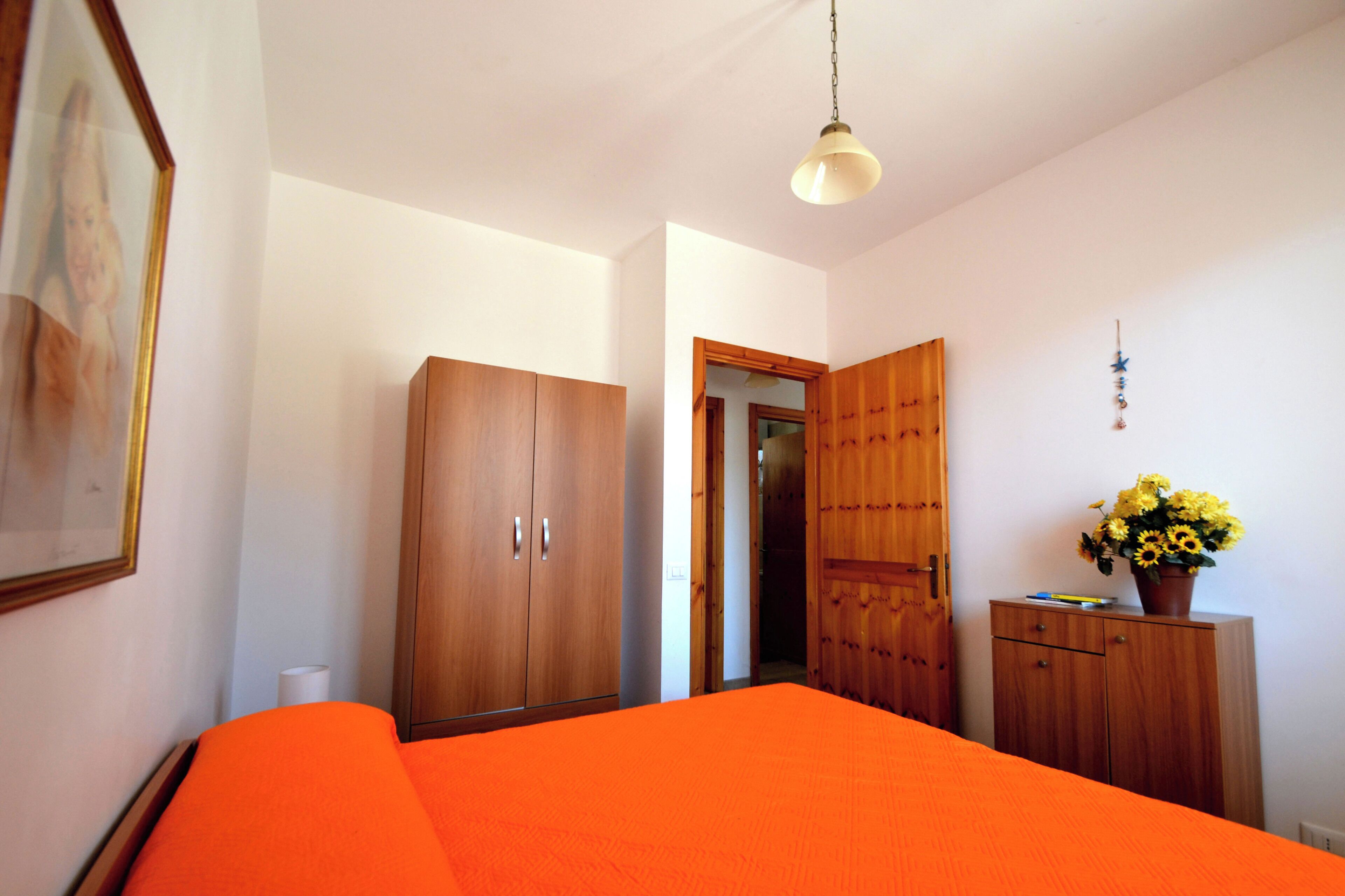 Une chambre à coucher comprenant un lit, une armoire et une porte donnant sur une autre pièce.