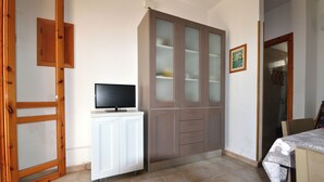 A room with a television on a white cabinet, a wooden wardrobe, and a tiled floor. - Teoma Holiday Home With Climate and Parking for 5 Guests (Melendugno)
