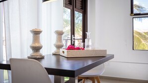 A dining area with a table, chairs, a decorative tray, and a window with a view. - Apartment With Outside Refreshing Cabin - Mi Cuna Close to Beach (Jan Thiel)