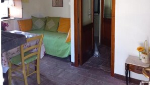 Ein gemütliches Zimmer mit einem Bett, einem Holzstuhl, einem Tisch und einer Pendelleuchte.